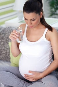 Pregnant woman drinking water and stroking her stomach